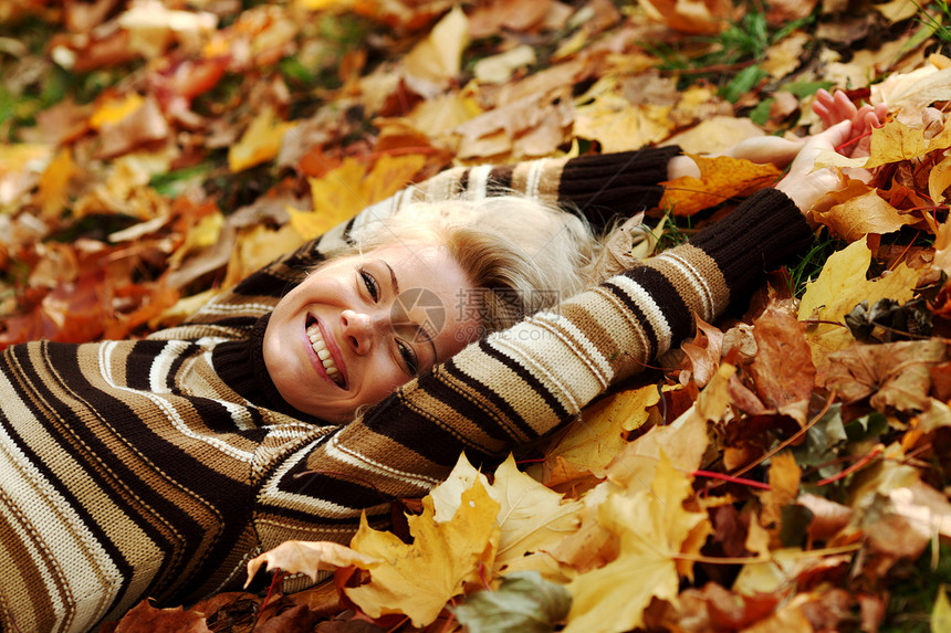 秋叶中的妇女脚尖眼睛乐趣公园感恩叶子女士头发幸福金发女郎成人图片