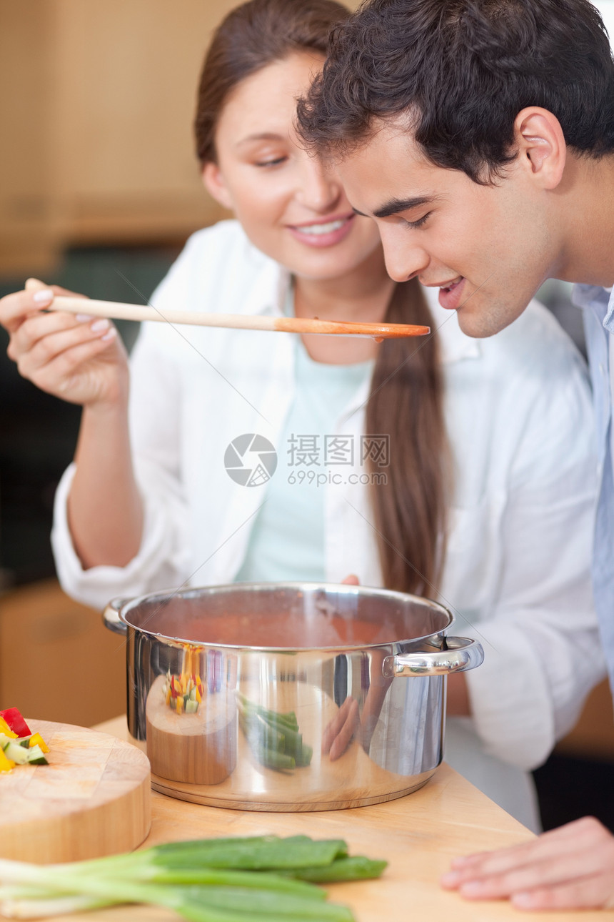 男人吃妻子酱汁的肖像年轻人蔬菜住宅丈夫火炉女性勺子喜悦晚餐房子图片