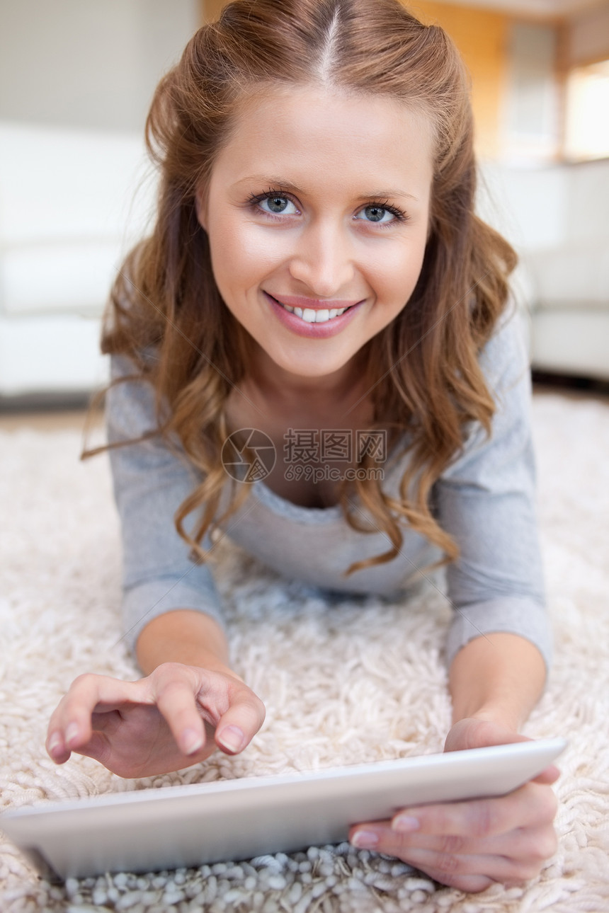 微笑的女人用平板电脑躺在地上图片