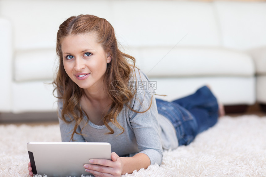 女人躺在地毯上 她的平板电脑图片