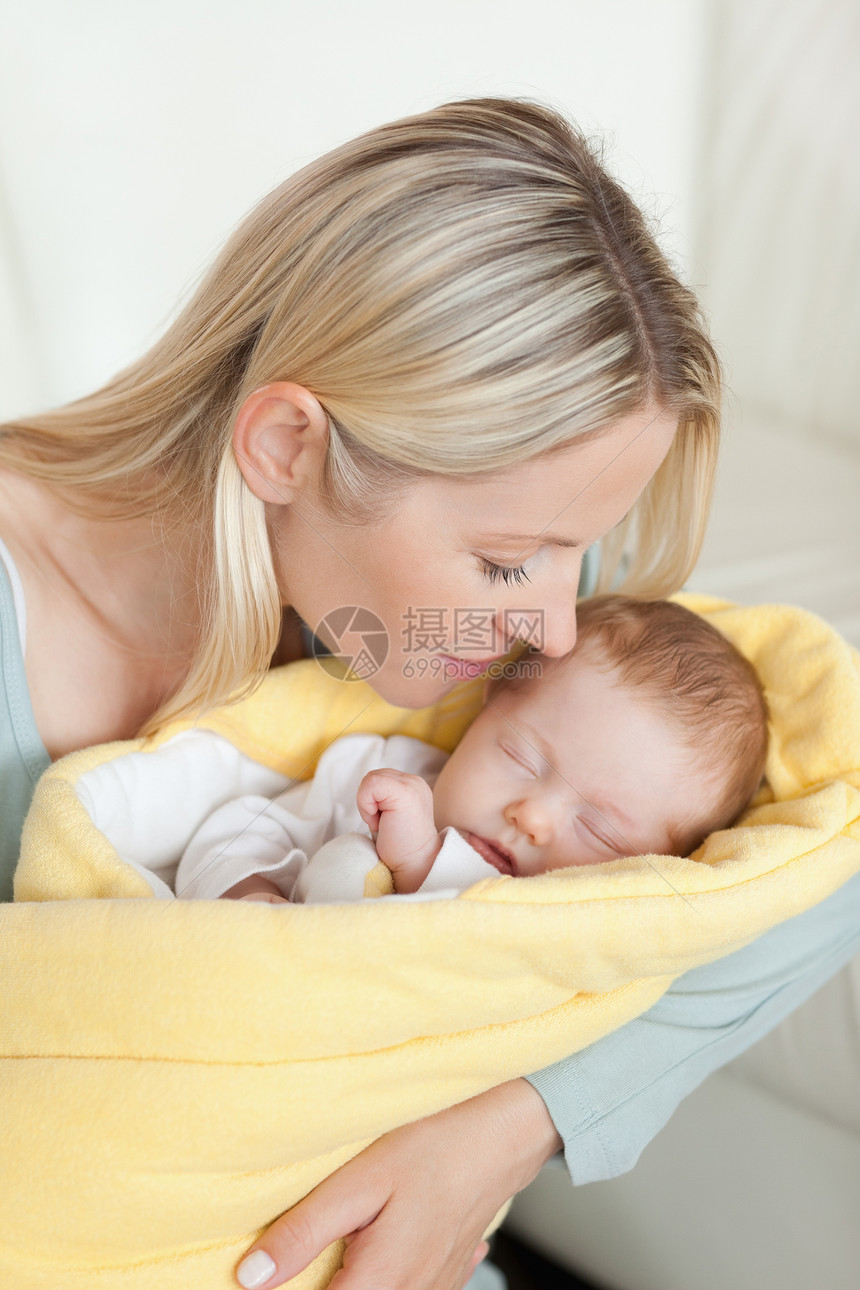 柔情的母亲亲吻她怀中睡着的婴儿图片