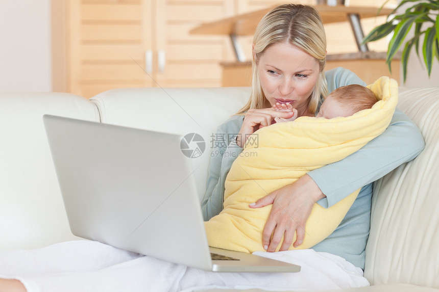 母亲在看笔记本电脑时抱着孩子图片