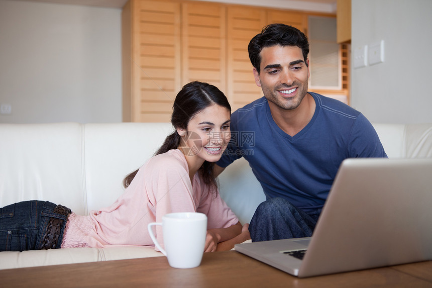 年轻夫妇在喝茶时使用笔记本电脑图片