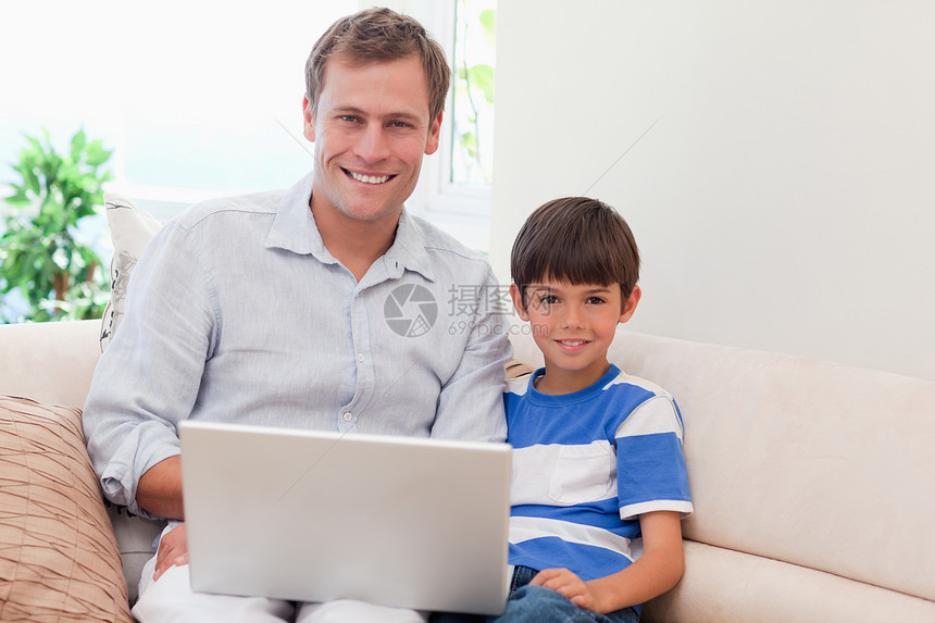 父亲和儿子 沙发上有笔记本电脑客厅闲暇外表男性网络快乐成年两个人乐趣娱乐图片