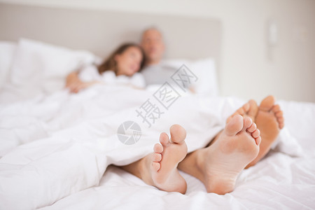 躺在床上的一对可爱的夫妇情怀赤脚投标微笑卧室妻子团结床单毯子夫妻男朋友高清图片素材