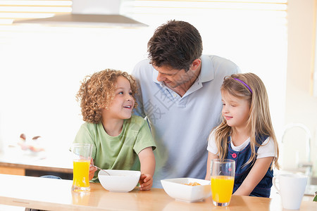 父亲和孩子在吃早餐时微笑的父亲与子女一起微笑厨房高清图片素材