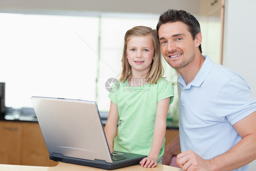 父亲和女儿使用笔记本电脑享受中年人团结童年家长两个人技术女孩互联网男人图片