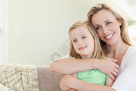 母亲在沙发上拥抱女儿团结幸福中年人姐姐家庭乐趣孩子快乐微笑感情爱高清图片素材