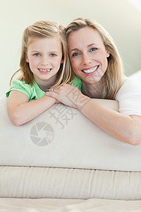 在沙发上微笑的快乐母亲和女儿女士高清图片素材
