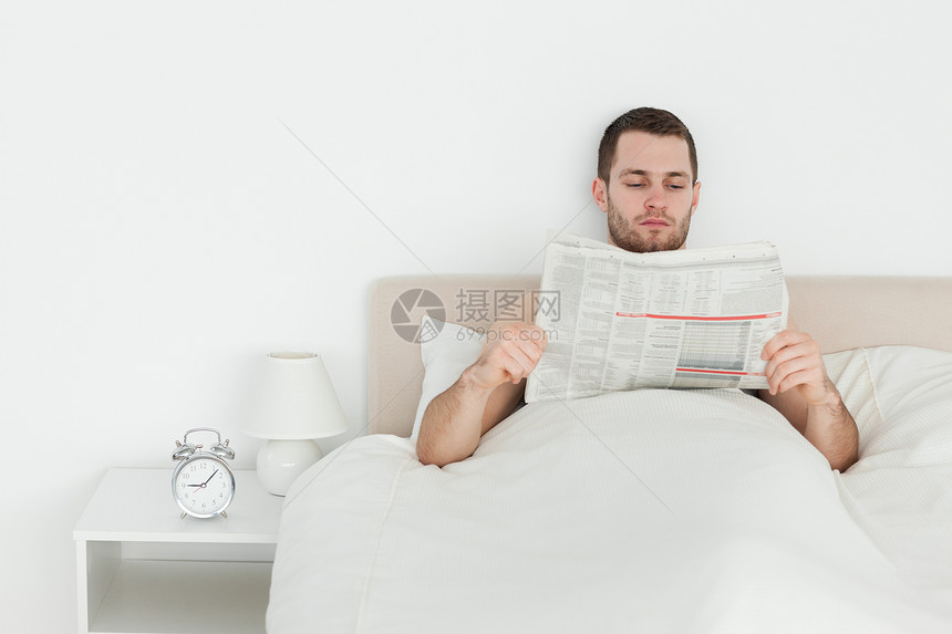 男人看报纸微笑房间外表商业床单阅读闲暇乐趣年轻人卧室图片