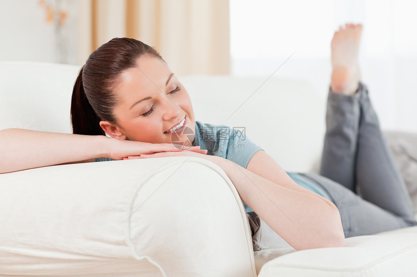 坐在沙发上时装扮着迷人的女人衣服亮度枕头窗帘女性房间青年冒充黑发女士图片
