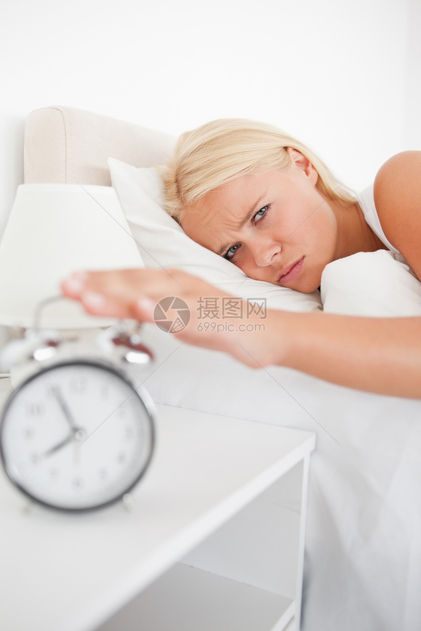一个疲倦女人的肖像 在一个闹钟响起时醒来图片