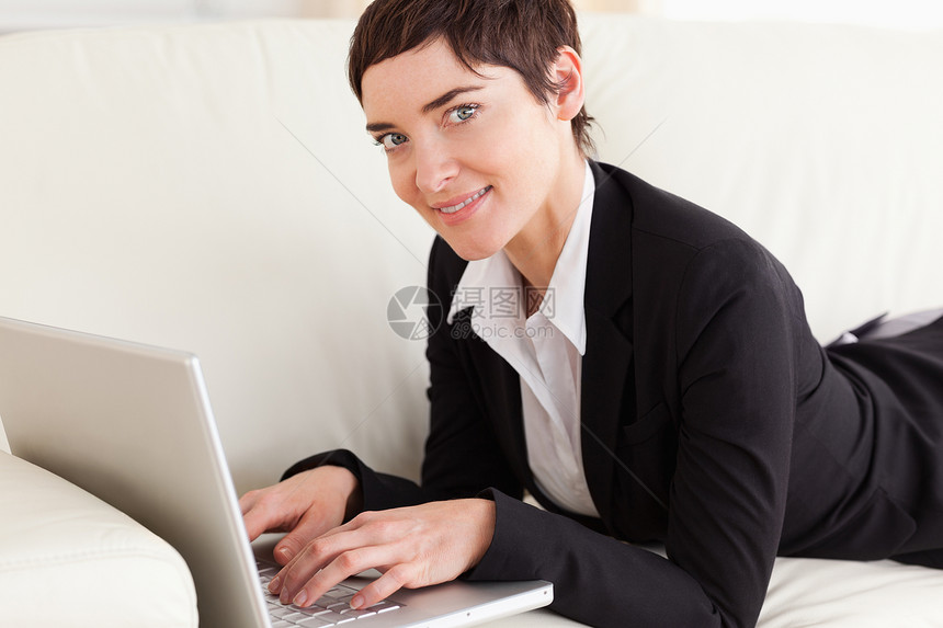 用笔记本电脑躺在沙发上的女商务人士图片