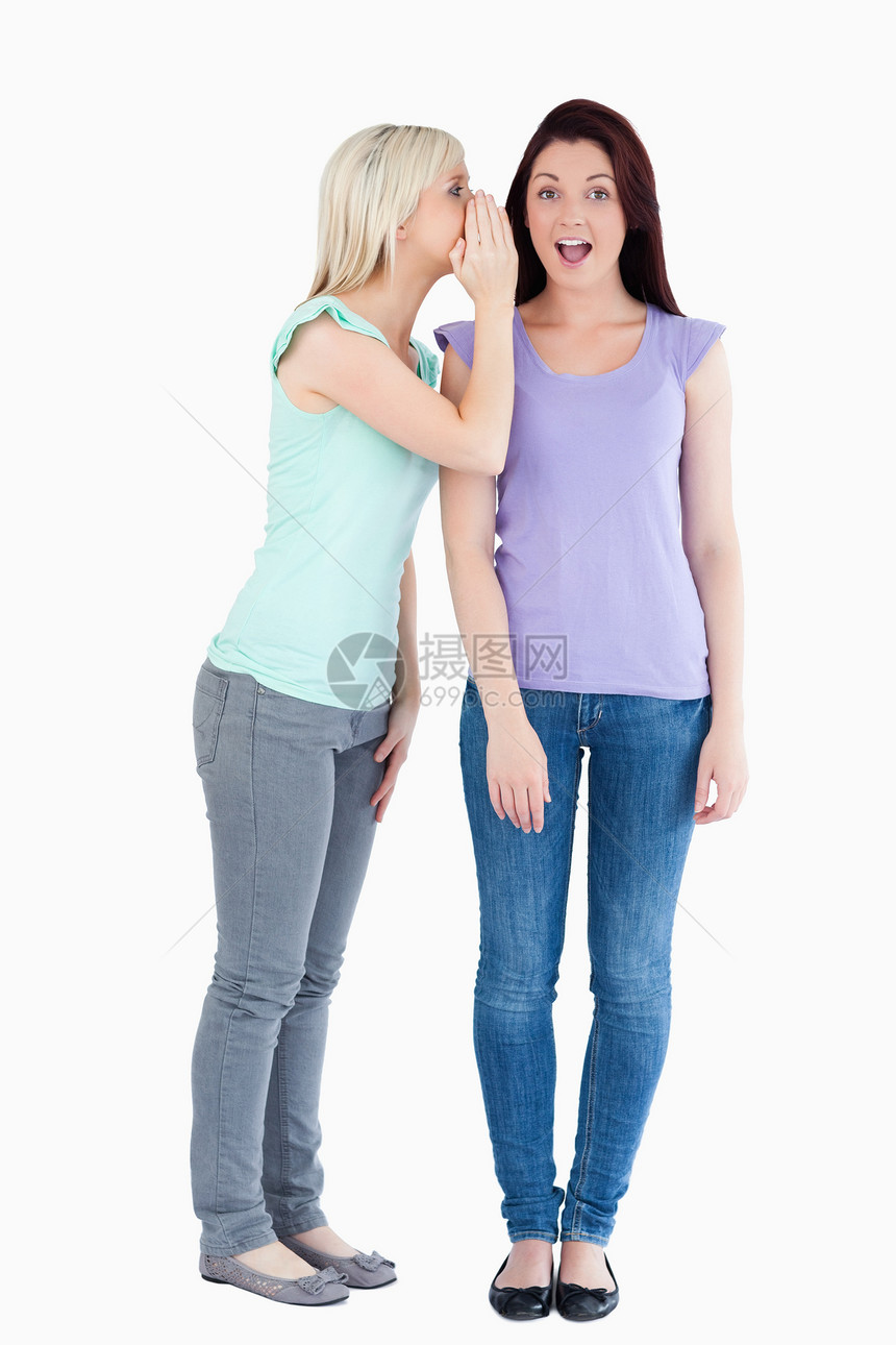 美丽的女人告诉朋友一个秘密外表身体耳语喜悦衬衫工作室女性图片