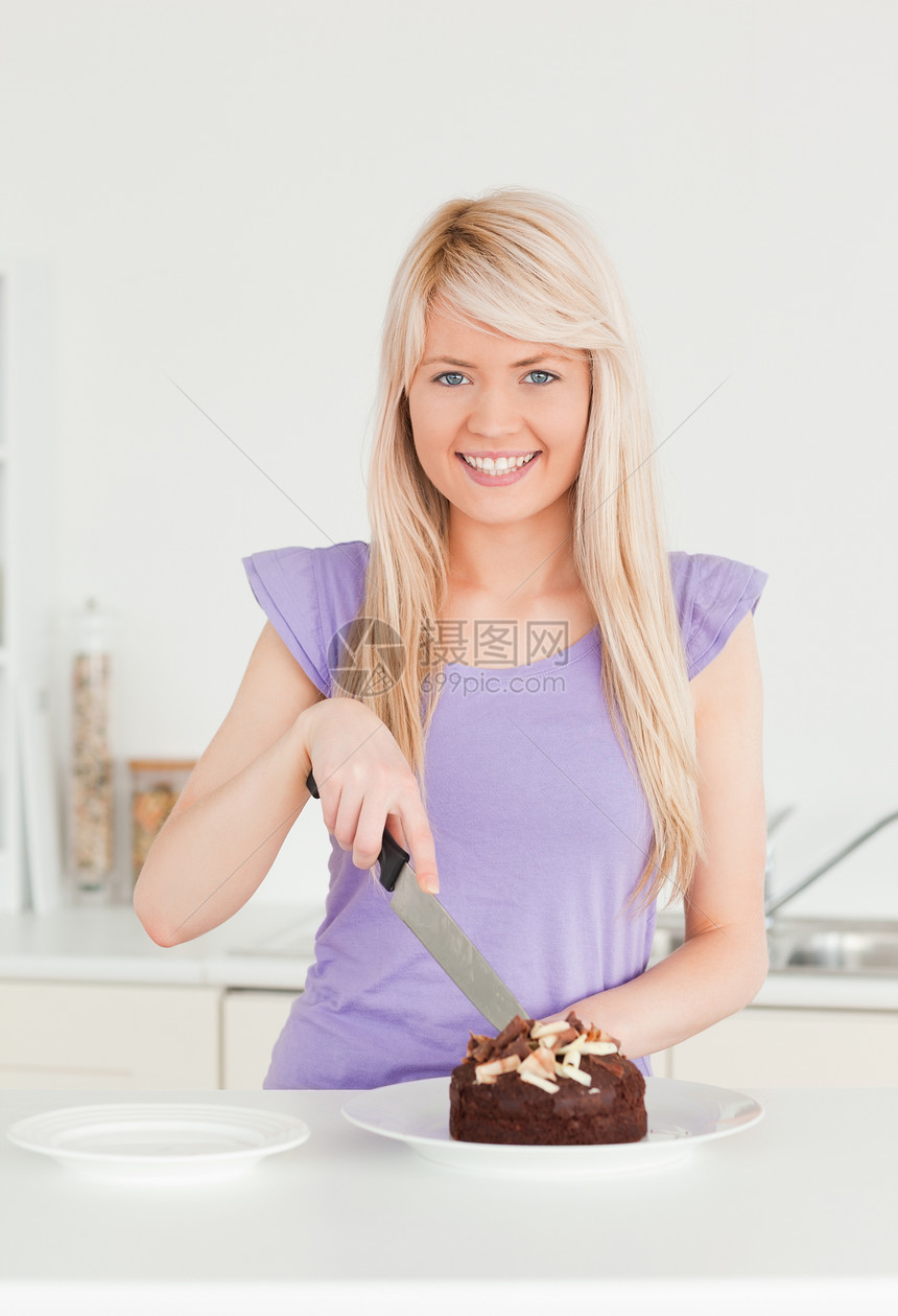 美丽的金发美女 在盘子里切蛋糕食物烹饪女士女性金发女郎厨师围裙面包快乐甜点图片