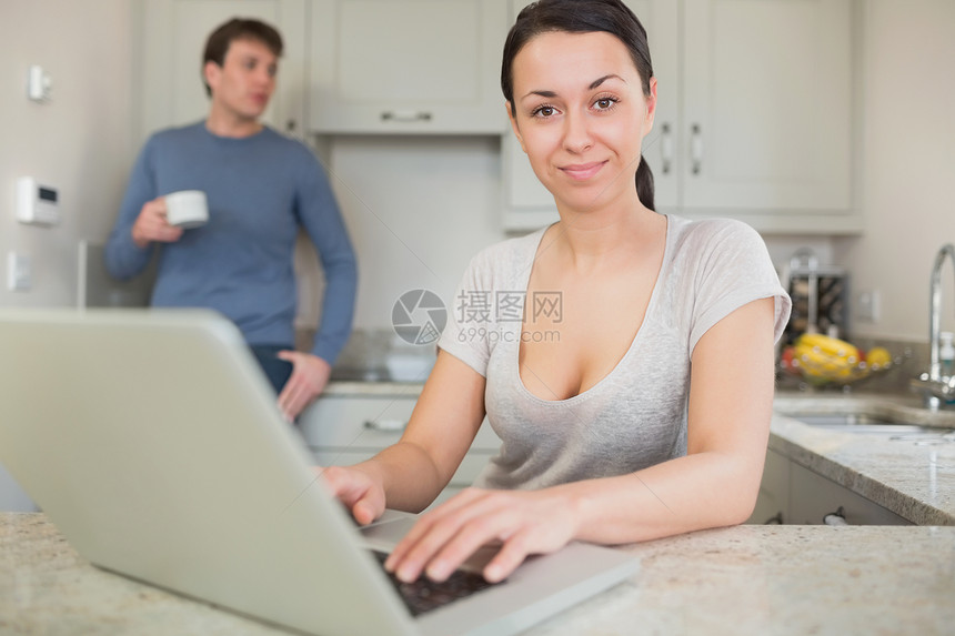 年轻妇女与男子一起使用笔记本电脑喝咖啡图片