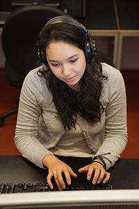 坐在电脑上戴耳机的妇女;妇女学者高清图片素材
