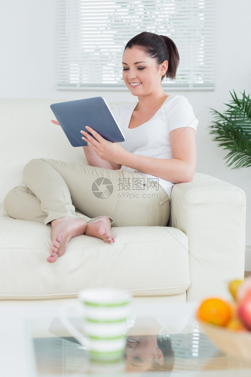 使用平板电脑在客厅里坐着的妇女图片