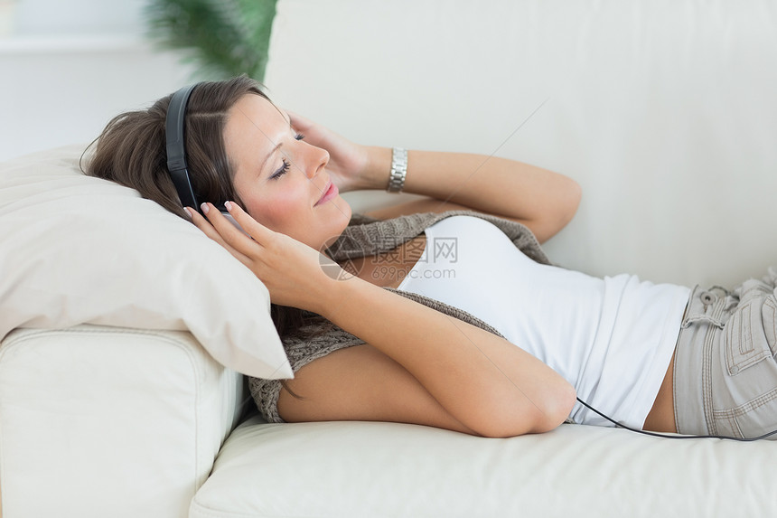 躺在沙发和听音乐的微笑的女人图片