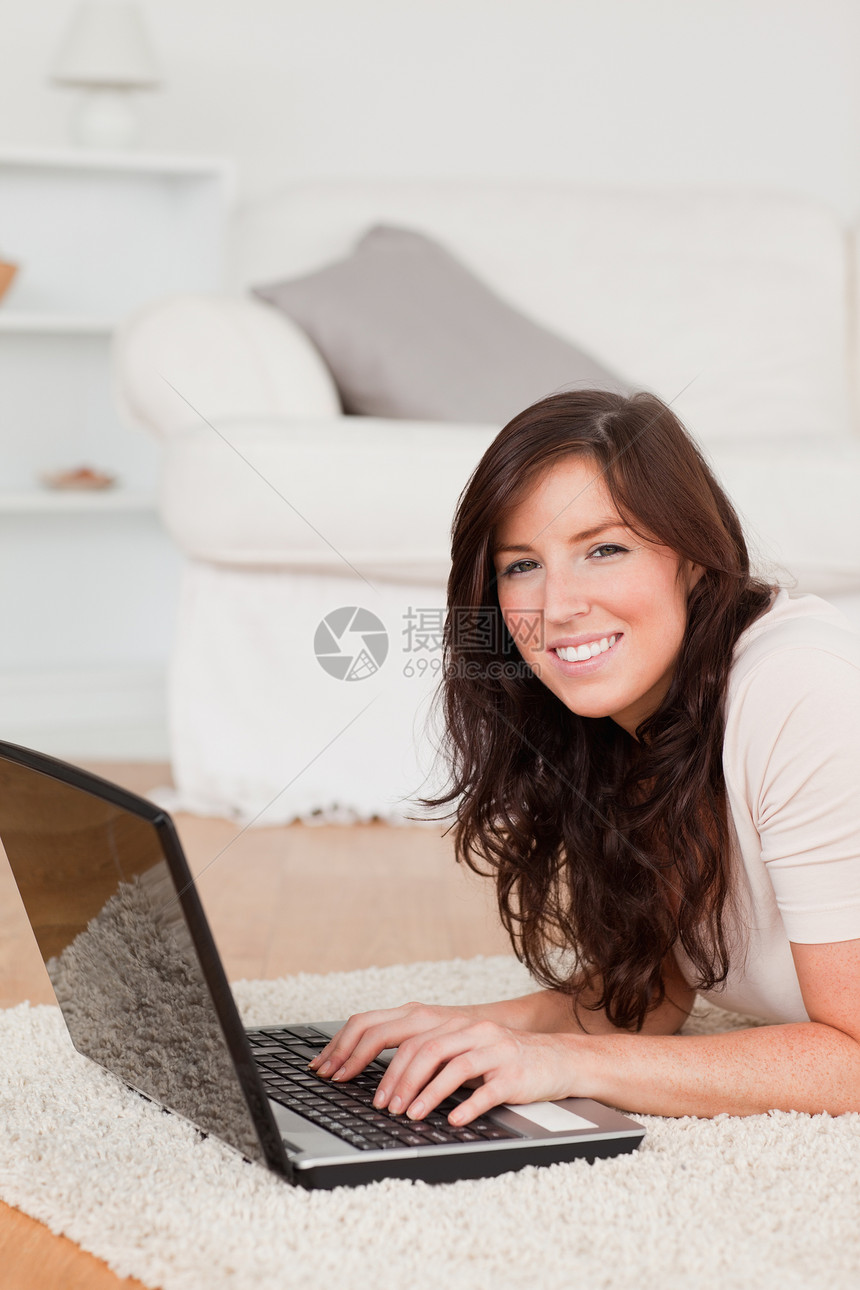 迷人的黑褐色女人在躺着时 用笔记本电脑放松图片