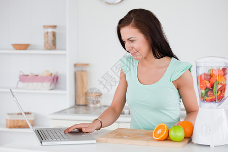 水果搅拌机妇女用笔记本电脑和水果在搅拌机里背景