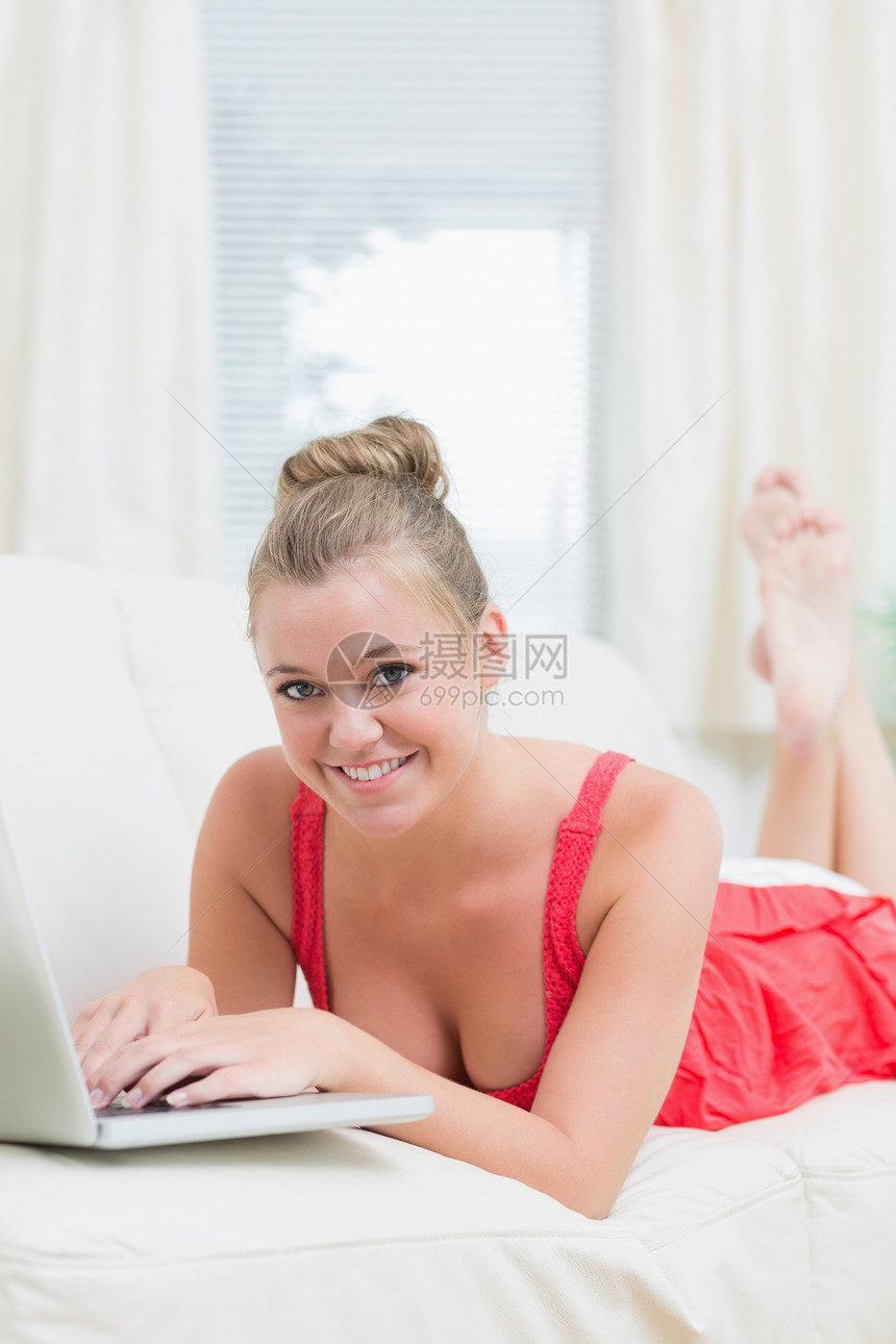 女人在沙发上用笔记本电脑放松时微笑图片