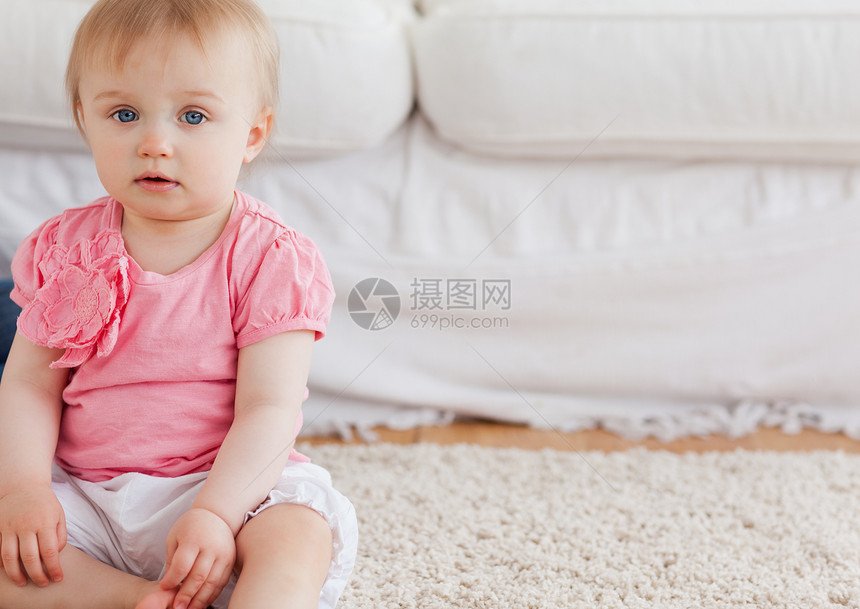 可爱的金发美女宝宝坐在雕刻上看着摄像机图片