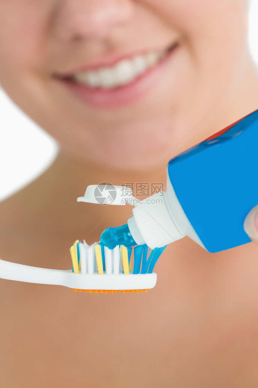 微笑的女人把牙膏放在牙刷上图片