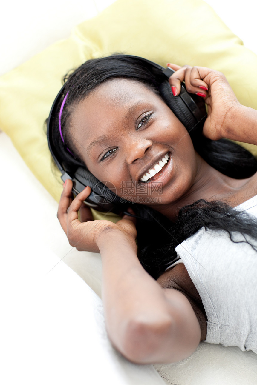 坐在沙发上用耳机听音乐的欢乐女人图片