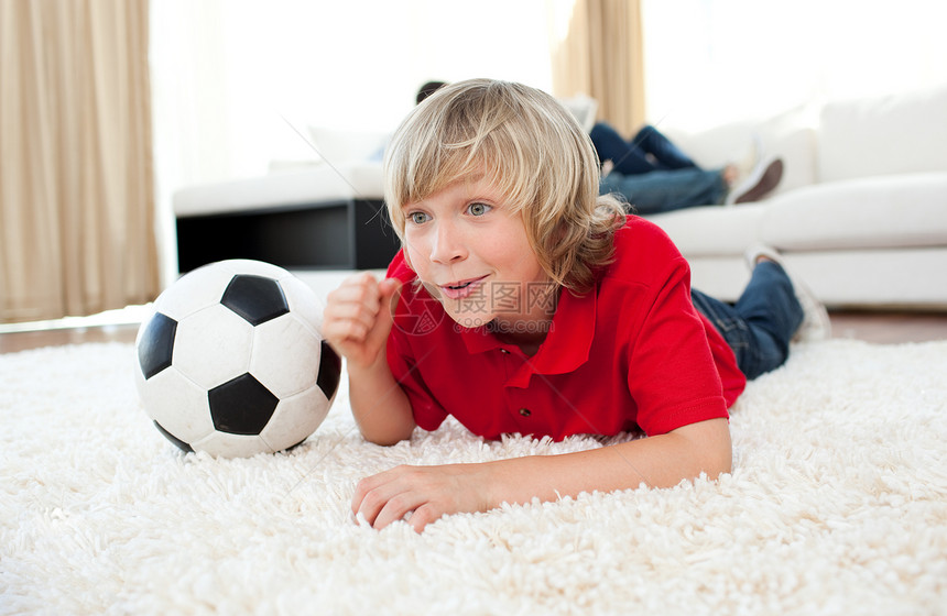 兴奋的男孩看足球比赛 躺在地板上图片