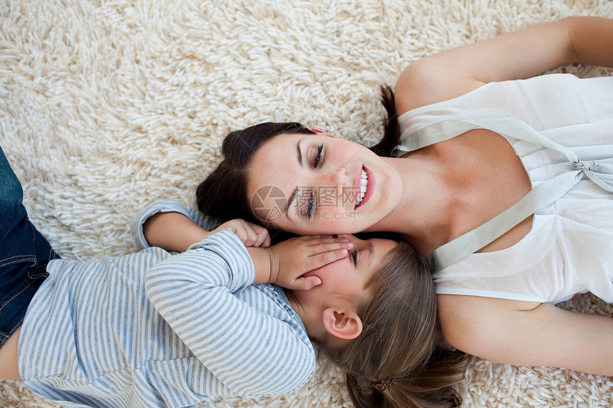 微笑的母亲和女儿躺在地上 躺在地板上图片