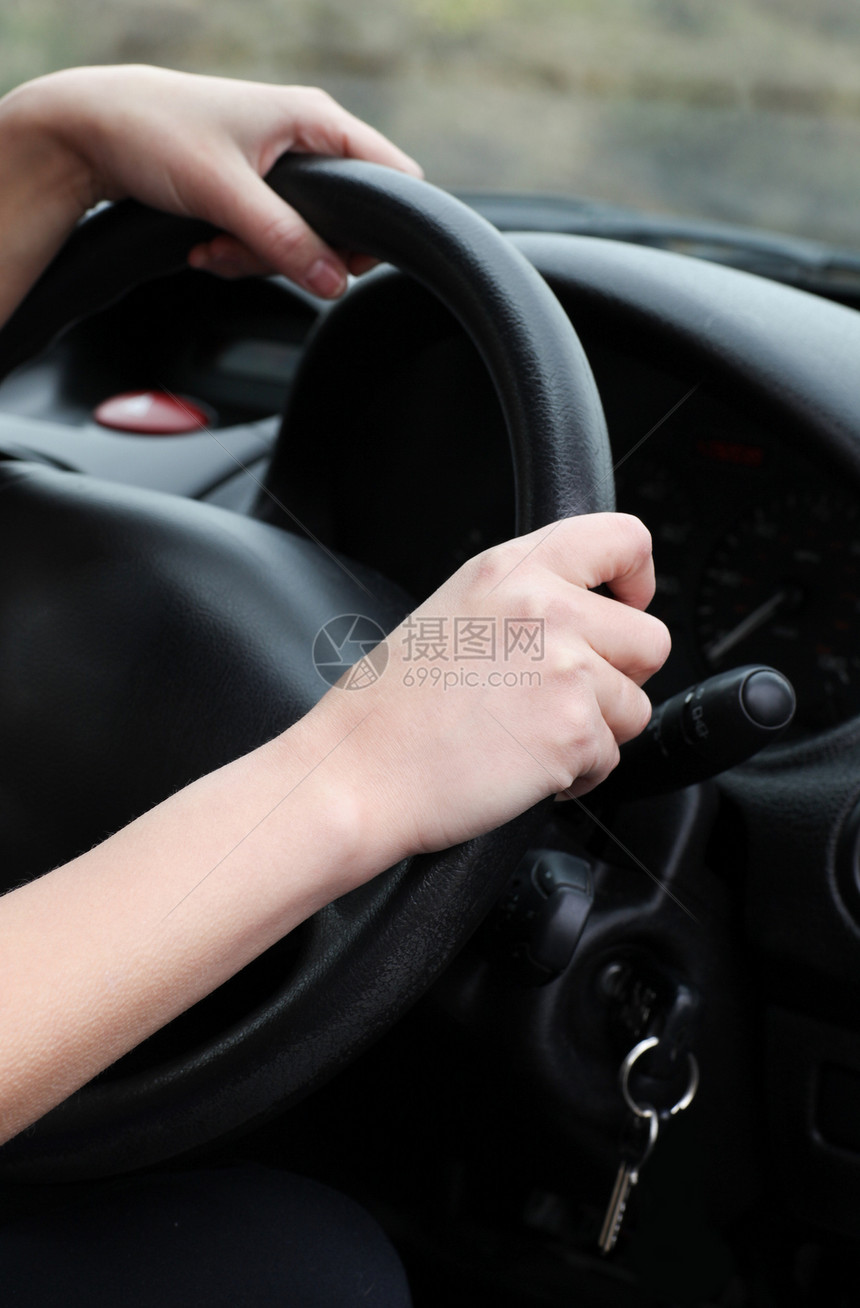 一名年轻女性驾驶员在车轮上闭合图片