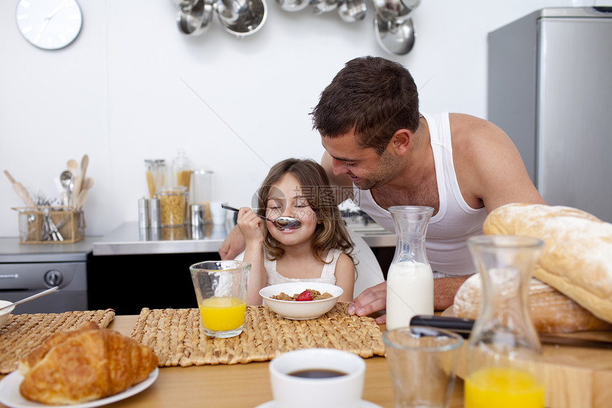 小女孩和父亲一起享受早餐的滋味家庭生活水果女儿童年父母孩子们孩子厨房食物图片