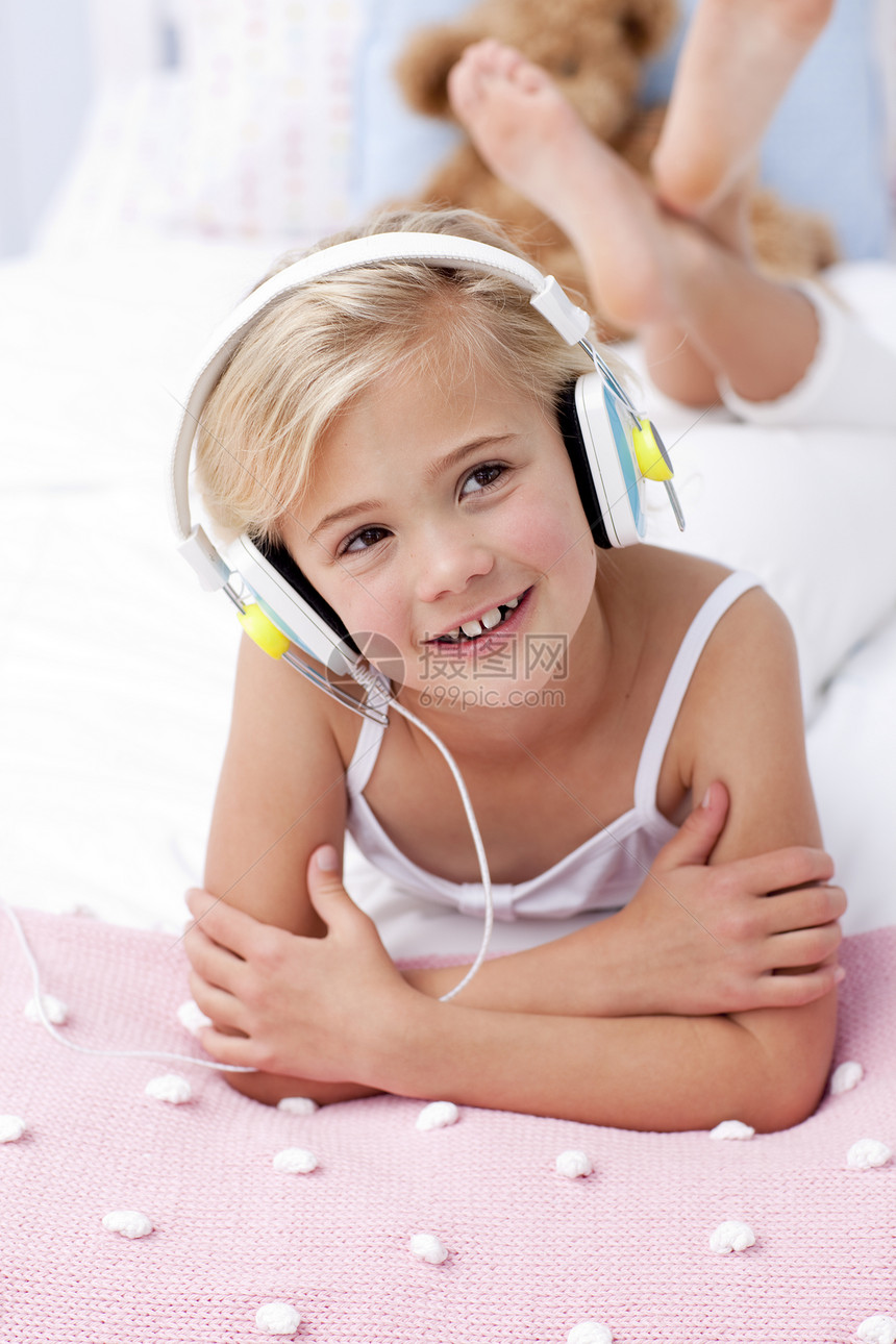 小女孩用耳机在床上收听音乐的歌声图片