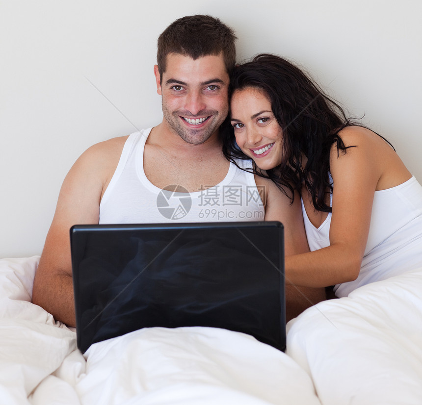 用笔记本电脑在卧室里笑着的情侣图片
