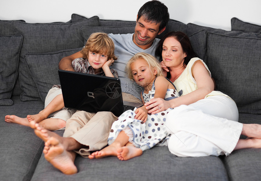 明亮的家庭在沙发上用笔记本电脑图片