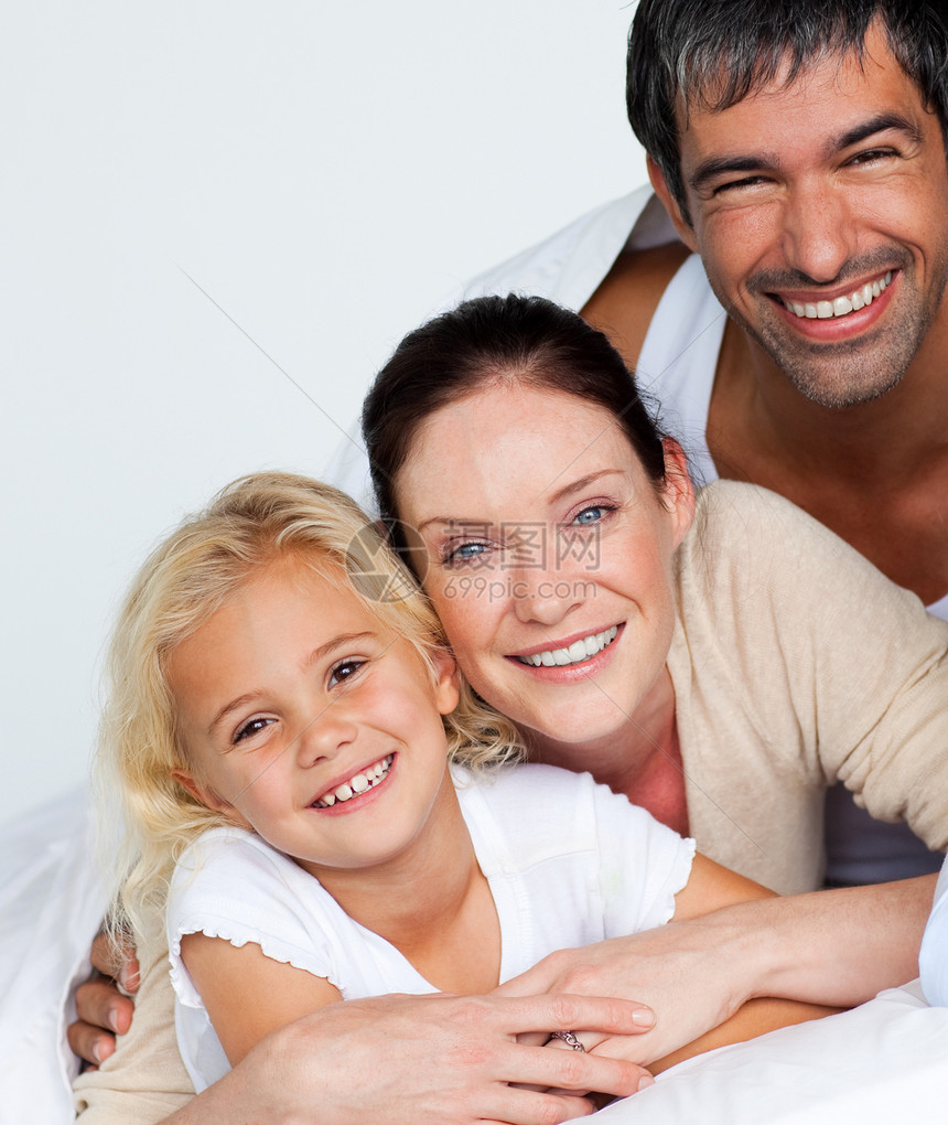 父母和女儿在床上对着镜头微笑图片