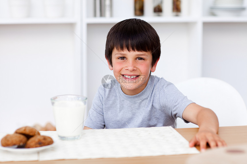 男孩在吃饼干和喝牛奶时微笑图片