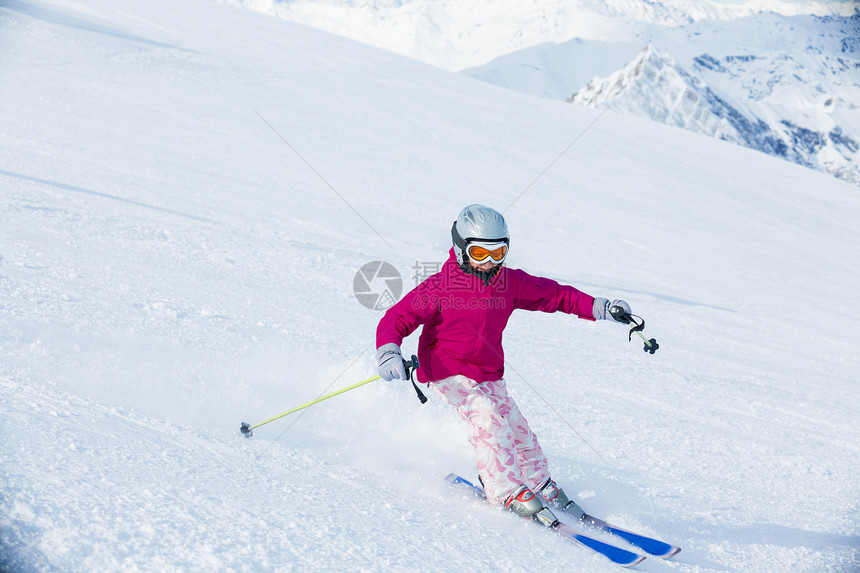 快乐的小女孩在下坡滑雪蓝色头盔爬坡娱乐套装运动山脉季节配备风镜图片