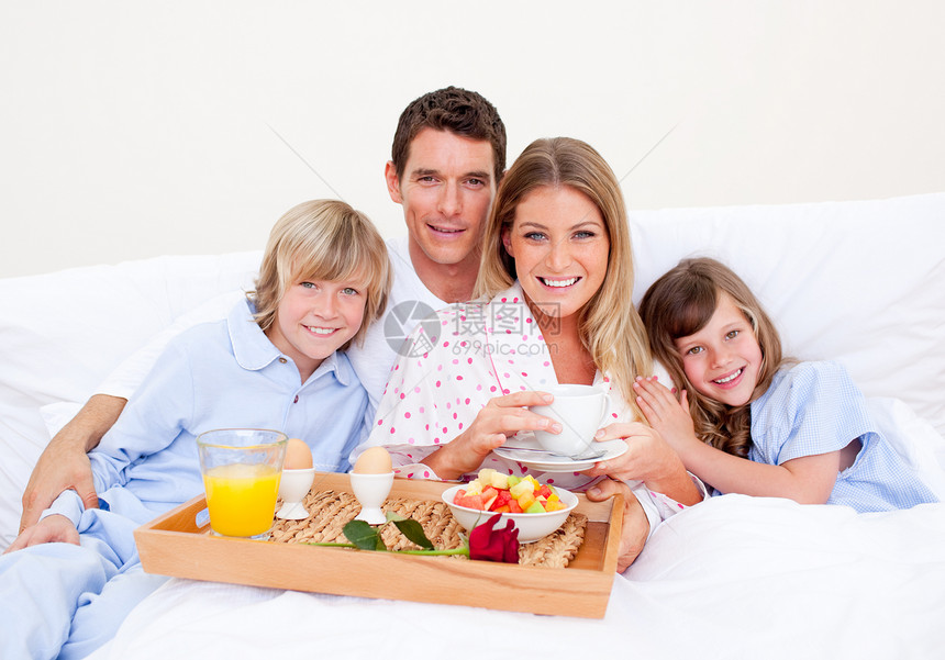 家人在床上吃早饭时微笑图片