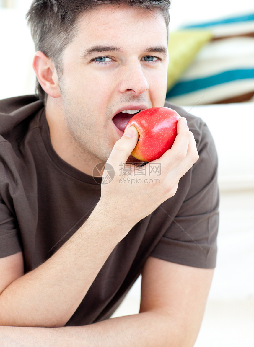 躺在地上吃着红苹果的年轻男人图片