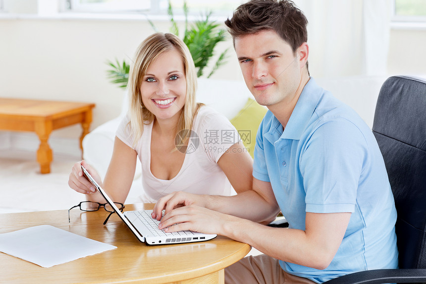 美艳的一对情侣在笔记本电脑上一起工作 坐在一张小报上图片