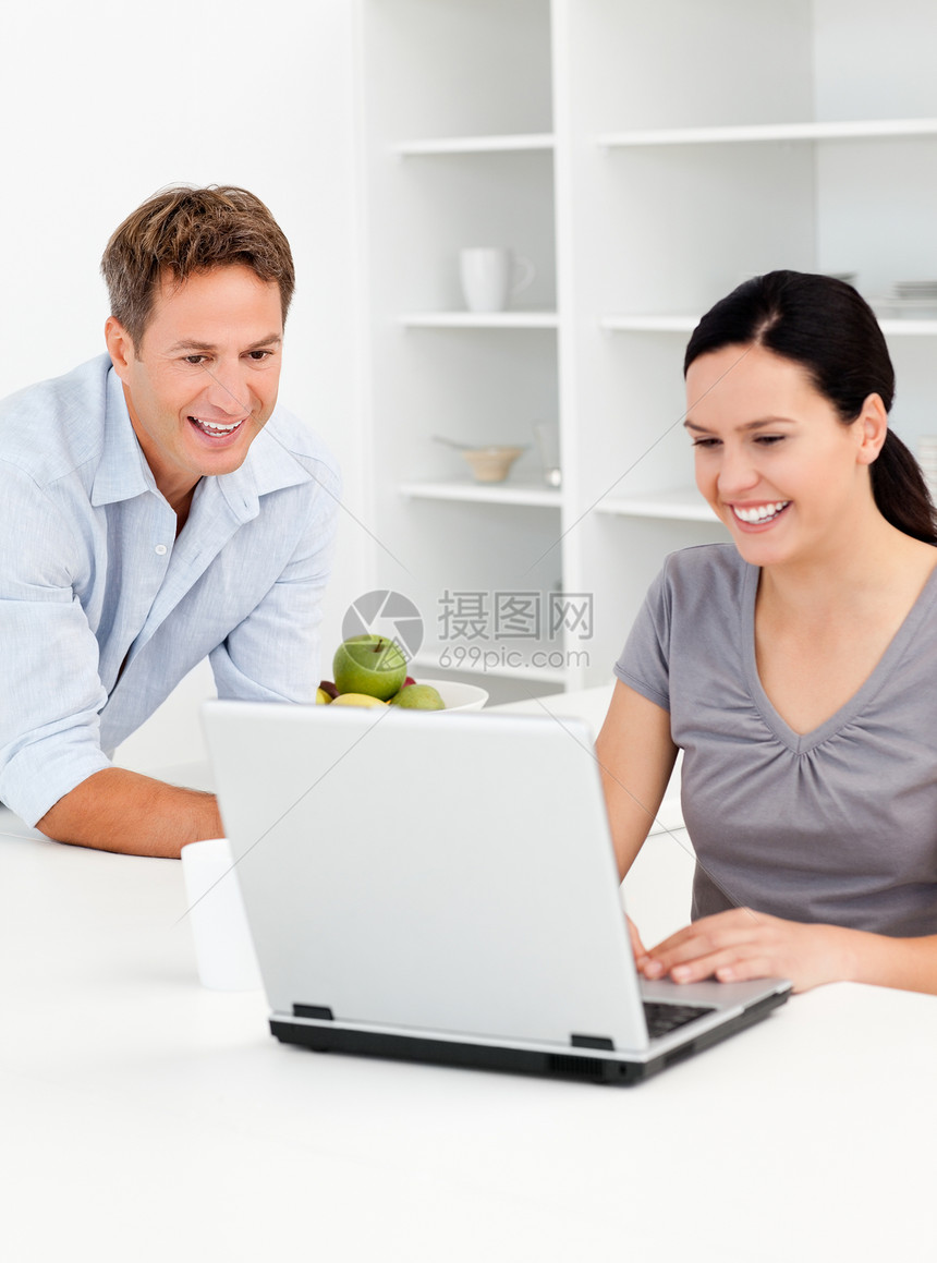 快乐的情侣在喝咖啡时看笔记本电脑图片