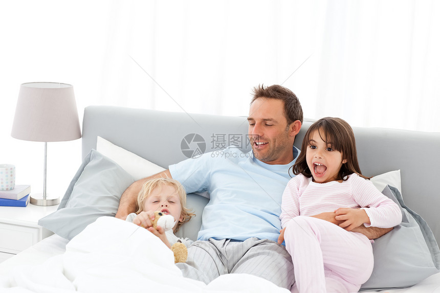 英俊的男人 躺在床上 和他的孩子在Waiking图片