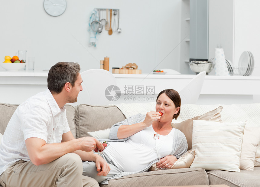与丈夫一起吃草莓的怀孕妇女微笑卧室夫妻享受幸福喜悦腹部女士几个月爸爸图片