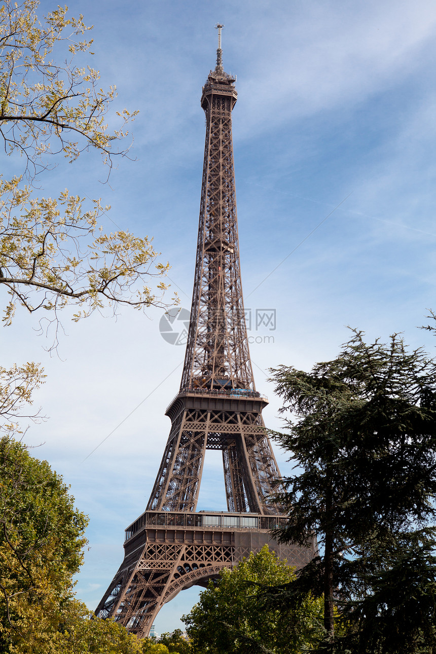 在法国巴黎的树木中穿越全国里程碑式埃菲尔塔文化蓝色公园建筑学国家首都天空游客假期树叶图片