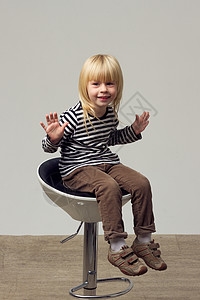 穿着牛仔裤的3岁女孩坐在高椅子上身体孩子靴子高脚椅头发卷曲金发女性夹克发型快乐的高清图片素材
