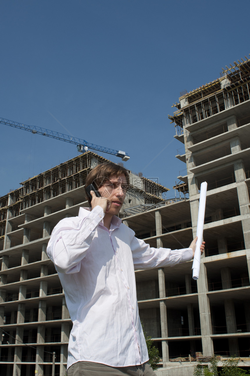 青年建筑师在建筑工地前通过电话发言图片