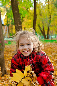 小女孩带着一堆黄叶子的黄色树叶背景图片