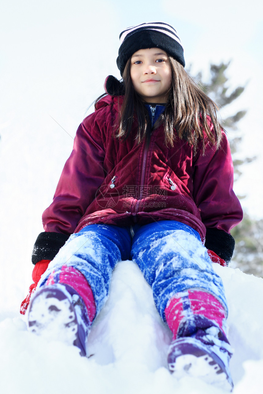 小女孩在冬天坐在一堆雪堆上空气孩子微笑爬坡手套女孩靴子夹克晴天帽子图片